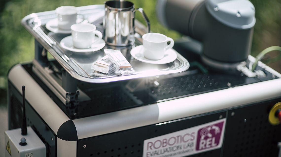 Kaffeegeschirr wird von einem Roboter trasnsportiert.